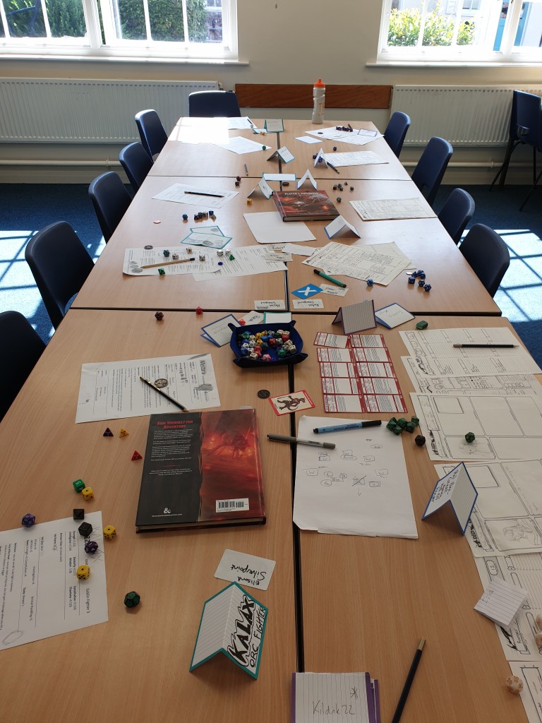An empty game table with lots of dice, notes, character sheets, card names, and D&D books